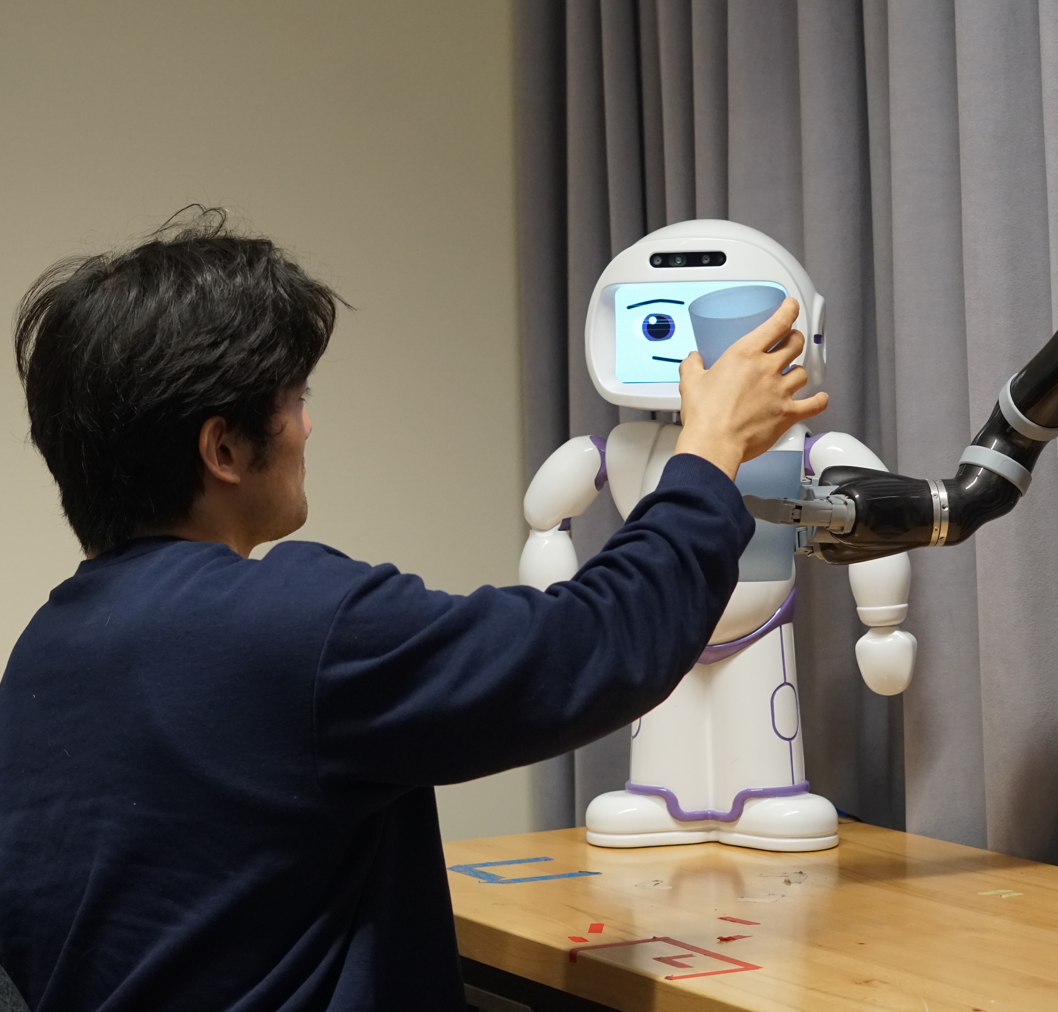 a user stacking a cup with an assistive robot.