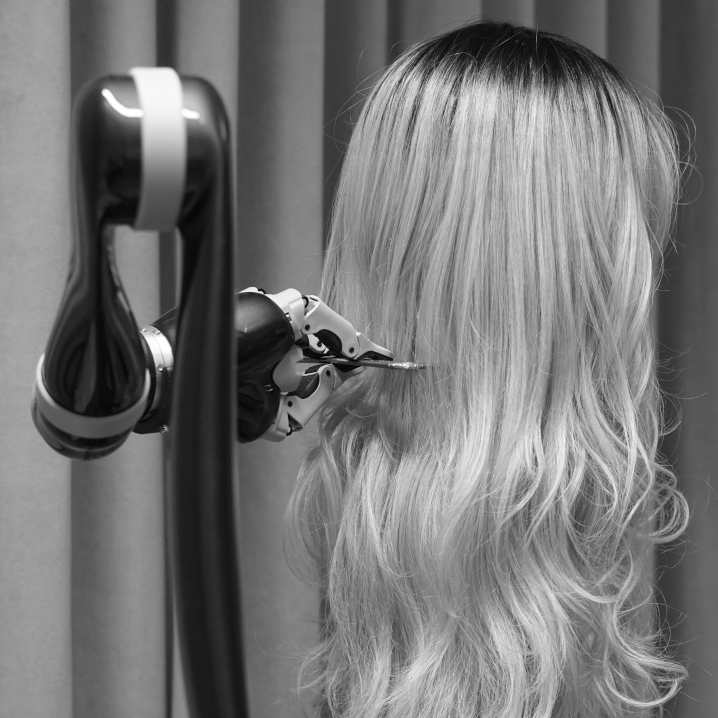 image of a robot arm combing a wig.